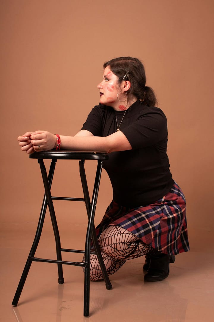 Stylish woman with a confident pose in studio setting with plaid skirt.